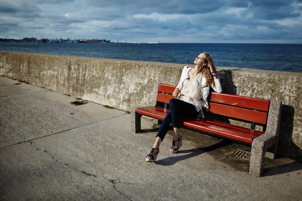 Красивая блондинка сидит на скамейке — стоковое фото