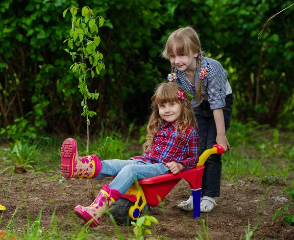 Two girls ride in wheelbarrow — Stock Photo, Image