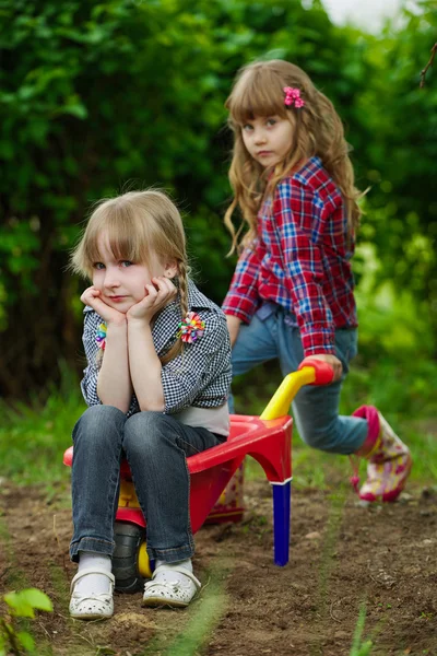 Two little girls ride in wheelbarrow — Stock Photo, Image