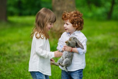 Erkek ve kız tavşanla oynuyor.
