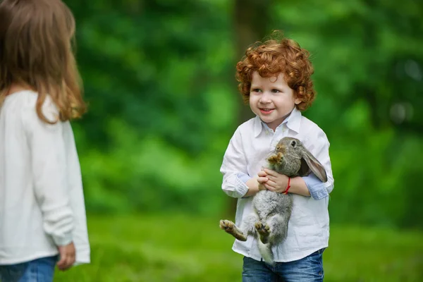 Menino e menina brincando com coelho — Fotografia de Stock