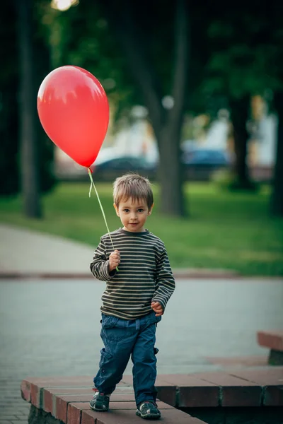 Piccolo ragazzo divertente con palloncino rosso — Foto Stock