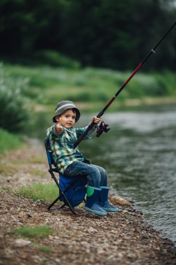 nehir kıyısında balık tutan çocuk