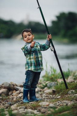 nehir kıyısında balık tutan çocuk