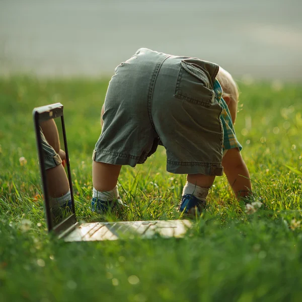 Liten pojke med laptop på gräs — Stockfoto