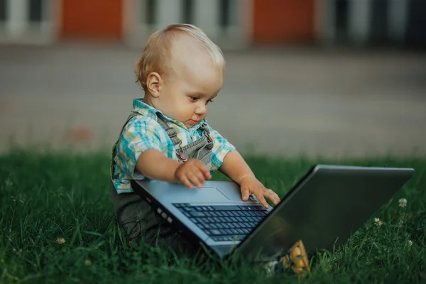 Menino com laptop na grama — Fotografia de Stock