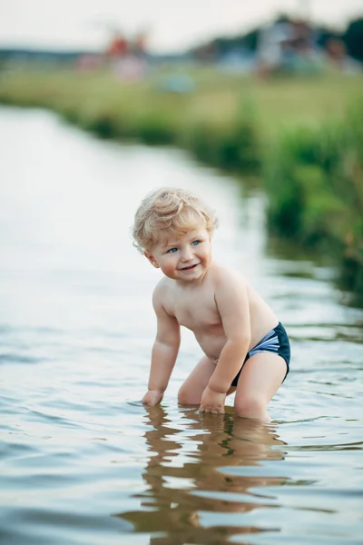 Liten rolig pojke spelar i vatten — Stockfoto