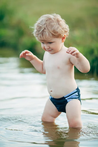 Menino engraçado brincando na água — Fotografia de Stock