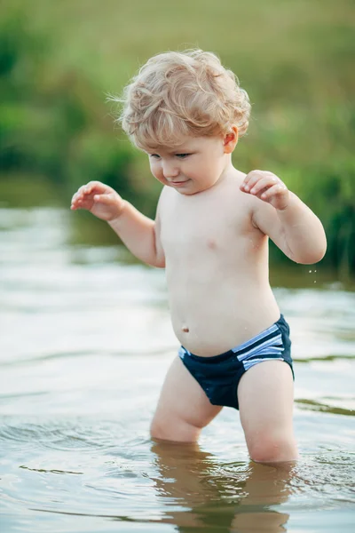 Liten rolig pojke spelar i vatten — Stockfoto