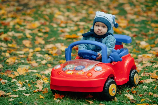 Маленький смішний хлопчик за кермом іграшкового автомобіля — стокове фото