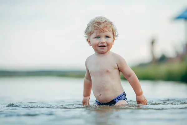 Маленький забавный мальчик играет в воде — стоковое фото