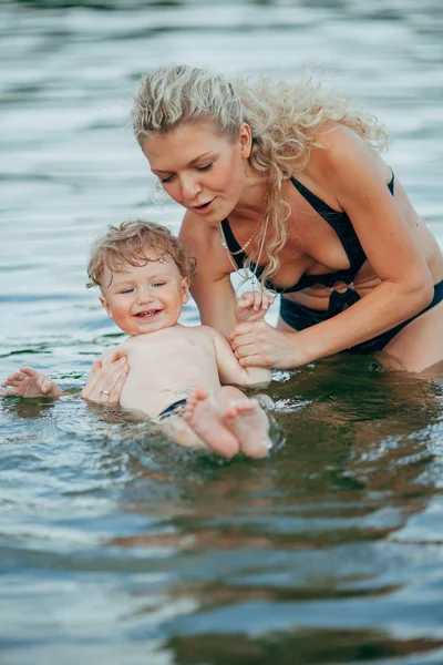 Giovane madre con suo figlio in acqua — Foto Stock