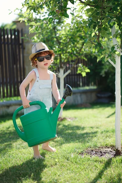 Liten pojke vattna träd i sommarträdgård — Stockfoto