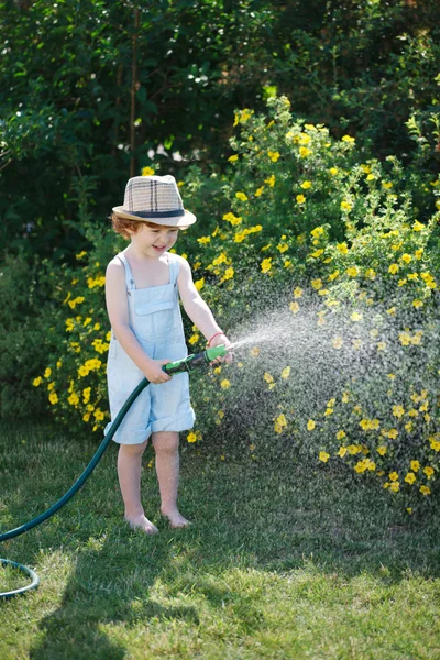 Kleiner Junge wässert den Garten mit Schlauch — Stockfoto