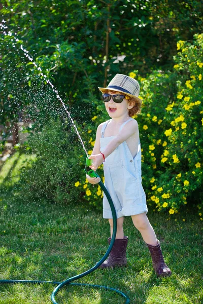 Kleiner Junge wässert den Garten mit Schlauch — Stockfoto