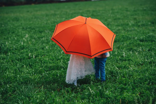 Menino e menina sob guarda-chuva vermelho — Fotografia de Stock