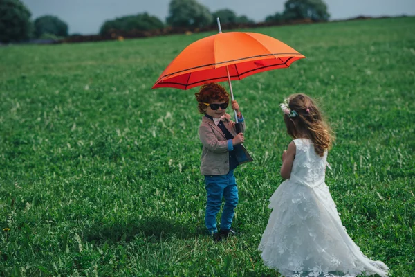 Мальчик и девочка под красным зонтиком — стоковое фото