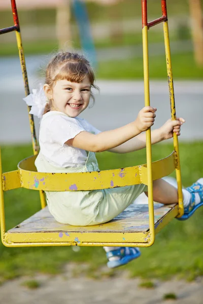 Liten glad tjej på gungorna — Stockfoto