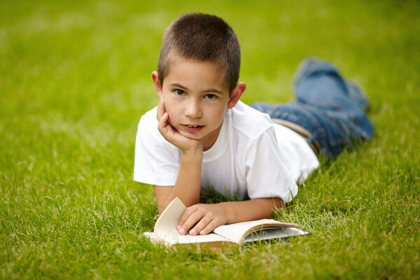 Маленький счастливый мальчик читает книгу
