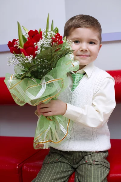 Menino com flores buquê sentado no sofá — Fotografia de Stock