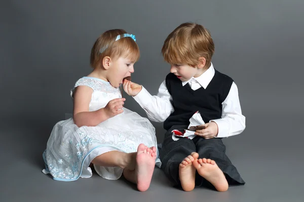 Menino ações com barra de chocolate menina — Fotografia de Stock