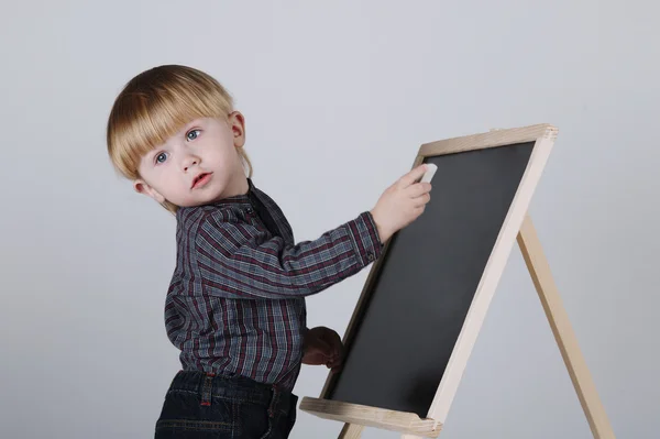 Хлопчик малює крейдою щось на дошці — стокове фото