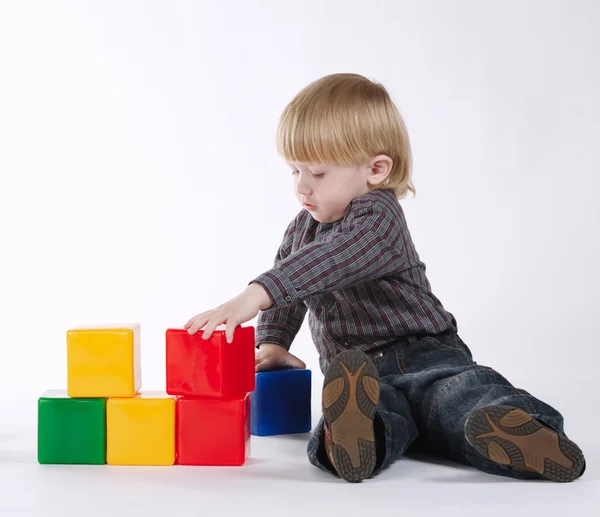 Petit garçon joue avec des cubes colorés — Photo