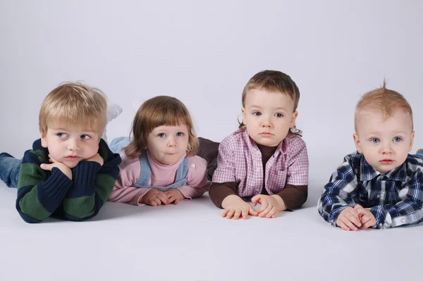 Fehér padlón fekvő boldog gyermekek — Stock Fotó