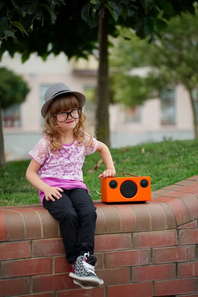 Hipster girl listens music on wireless retro looking speaker — Stock Photo, Image