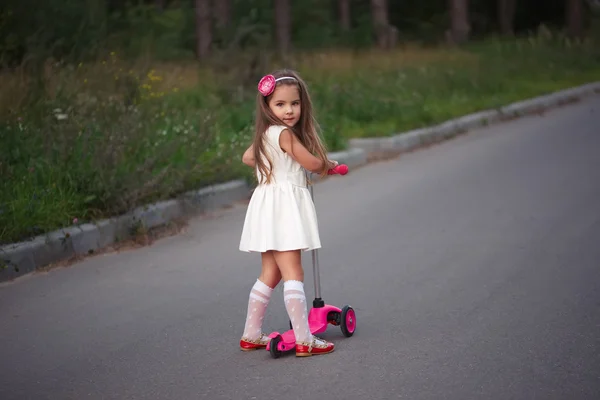 Malá holčička s koloběžkou na silnici — Stock fotografie