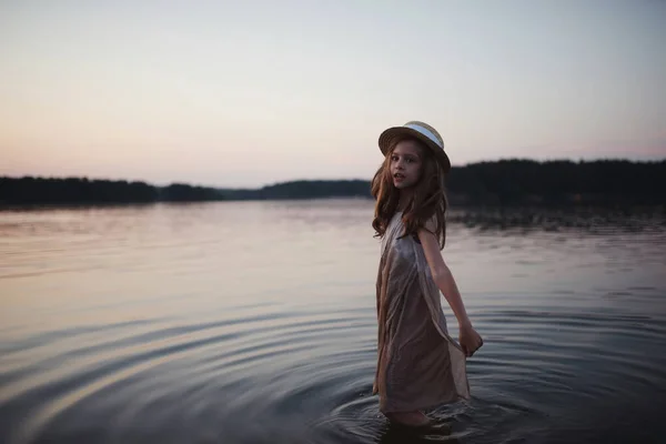 Pequeña linda chica con el pelo largo en el lago — Foto de Stock