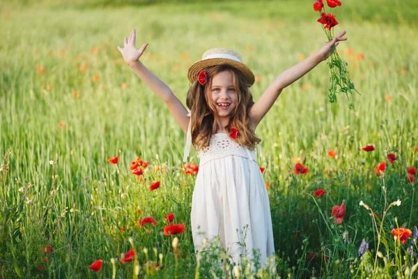 Schattig klein meisje in weide met rode klaprozen — Stockfoto