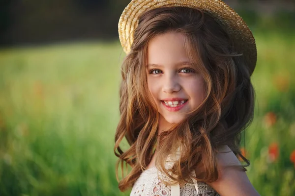 Schattig klein meisje in weide met rode klaprozen — Stockfoto
