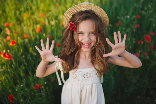 Menina bonito no prado com papoilas vermelhas — Fotografia de Stock