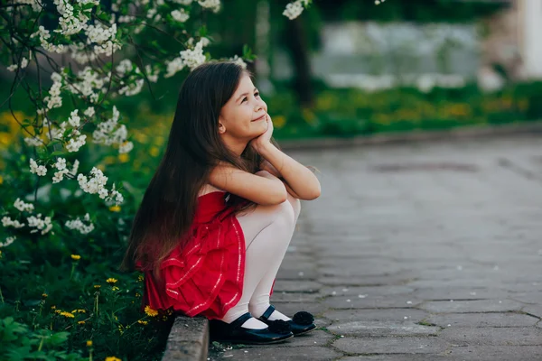 Menina bonita sentada sob a árvore de cereja — Fotografia de Stock