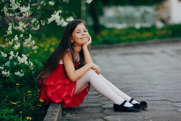 Menina bonita sentada sob a árvore de cereja — Fotografia de Stock