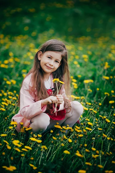 Piccola ragazza seduta nel campo di fiori e sentirsi felici — Foto Stock