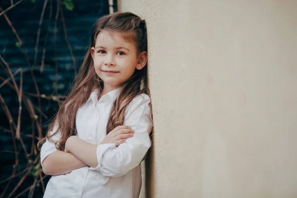 Küçük ve şirin bir kız kalmak açık duvarın yanında — Stok fotoğraf