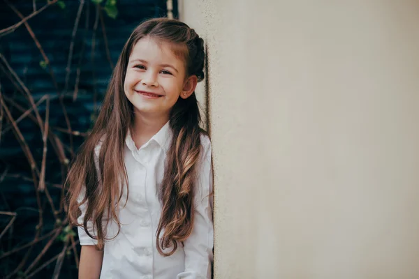 Küçük ve şirin bir kız kalmak açık duvarın yanında — Stok fotoğraf