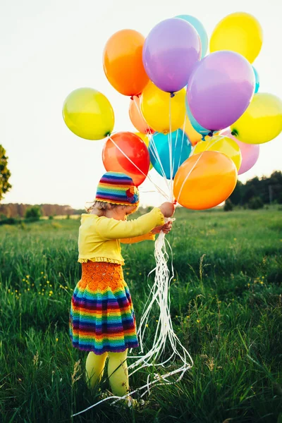 Kleines Mädchen mit bunten Luftballons — Stockfoto