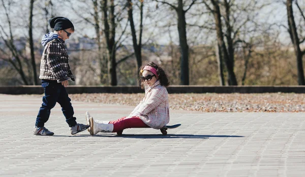 Chłopiec i dziewczynka na łyżwach na ulicy — Zdjęcie stockowe