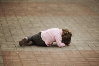 crying girl lying on asphalt clipart