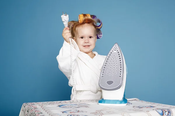 Pequena dona de casa com ferro no fundo azul — Fotografia de Stock