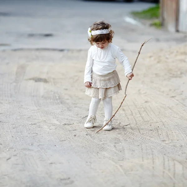 Carino bambina gioca con bastone — Foto Stock