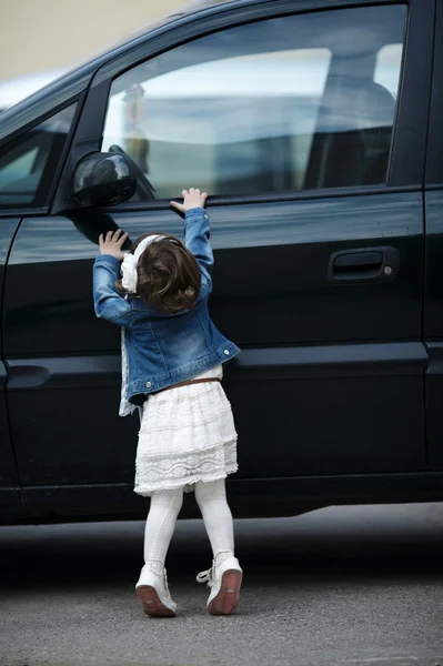 Маленькая девочка хочет открыть машину — стоковое фото