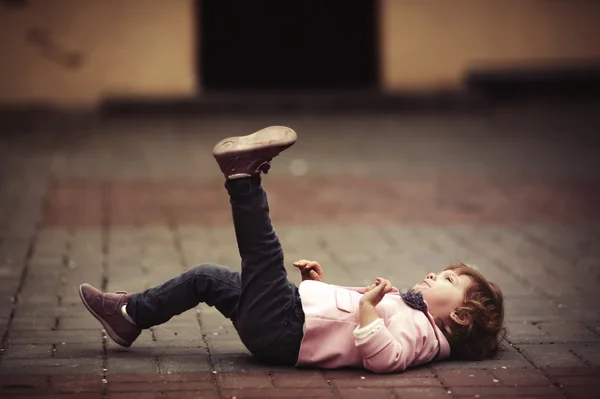Linda niña acostada sobre asfalto — Foto de Stock
