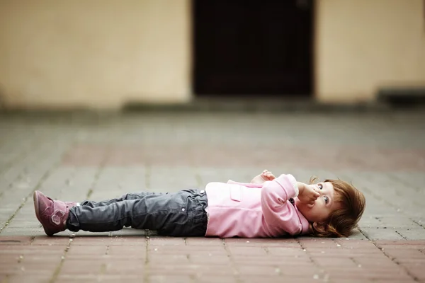 Маленькая девочка лежит на асфальтовом портрете — стоковое фото