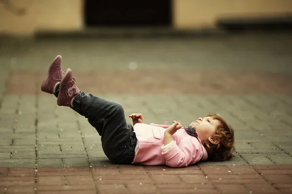 Little girl lying on asphalt portrait — Stock Photo, Image