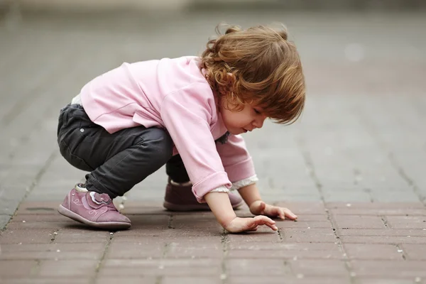 Little girl lying on asphalt portrait — Stock Photo, Image