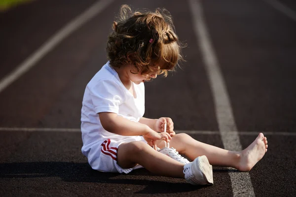 Красивая маленькая девочка учится завязывать шнурки — стоковое фото